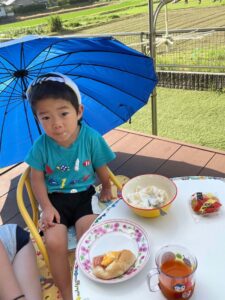 外で日傘を使いながら食べるケン